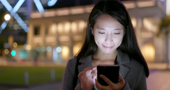 Business woman working on smart phone at night