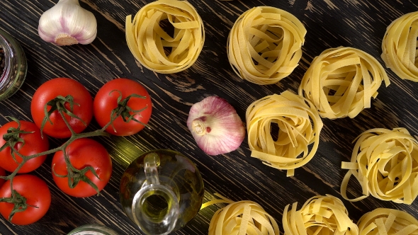 Pasta, Oil, Tomatos and Garlic on Wooden Background