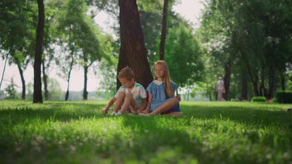 Laughing Kids Sitting Under Tree in Green Park