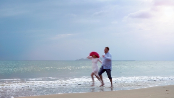 Man and a Girl Running Along the Beach