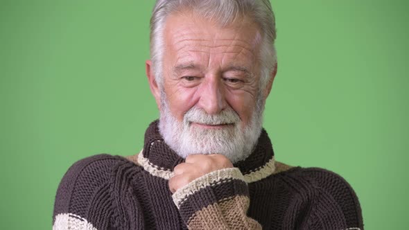 Handsome Senior Bearded Man Wearing Warm Clothing Against Green Background