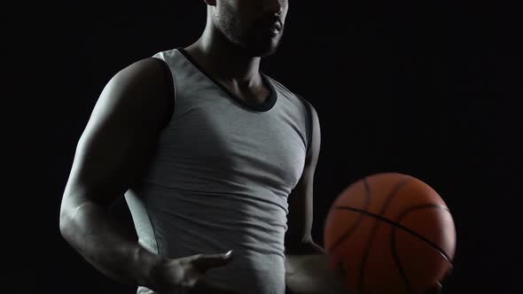 Tall Black Athlete Carrying Basket Ball in Hands, Thinking About Game Strategy