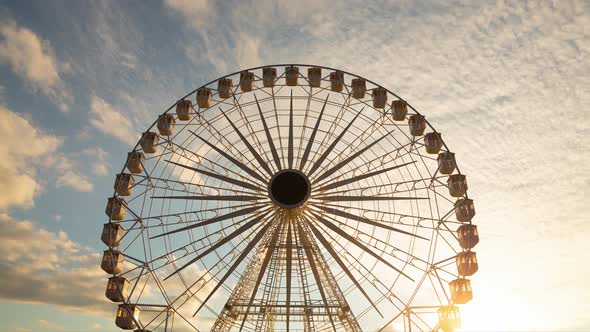 Ferris wheel silhouette at sunset - time lapse - against beautiful clouds in the sky