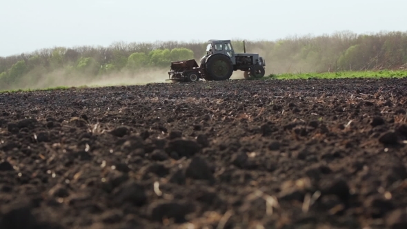 Farmer Sowing a Plowed Field With Tractor