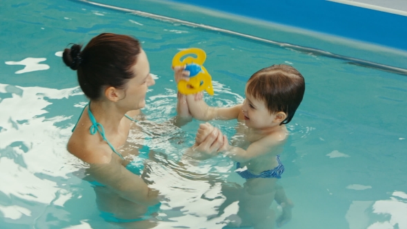 Cheery Mother with Her Funny Baby Laughing in the Pool