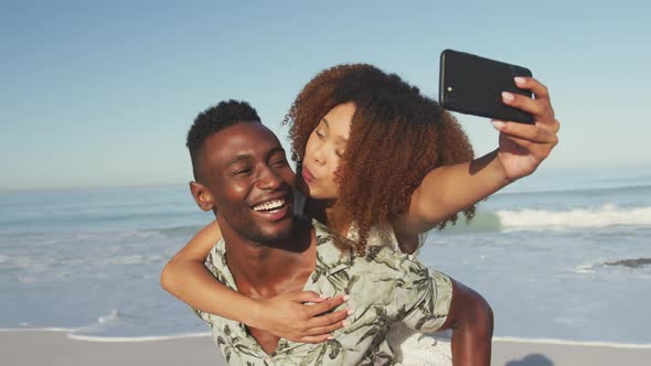 African American couple taking a selfie at beach