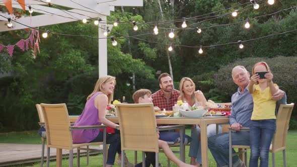 Three generation family taking a selfie while enjoying lunch outdoors