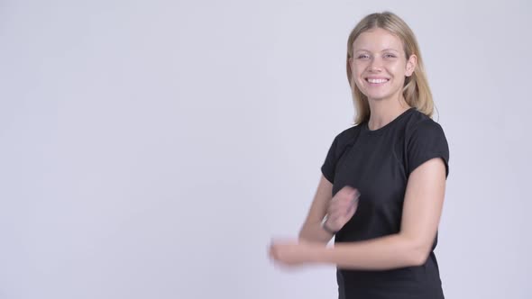Profile View of Young Happy Blonde Woman Looking at Camera with Arms Crossed