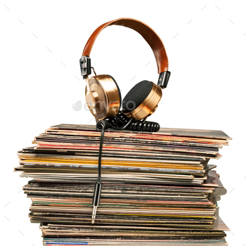 dphones with jack plug lying on the stack of retro jazz rock pop shabby grunge vinyl records on white background.