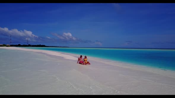 Guy and girl sunbathing on tropical resort beach lifestyle by shallow ocean with white sand backgrou