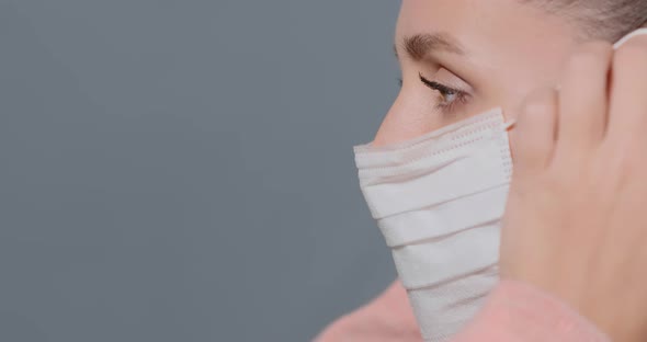 Young Woman Puts White Disposable Mask on Face and Fixes