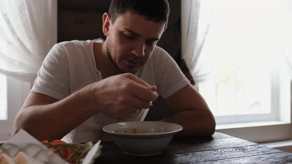 Young Man Eating Soup in a Restaurant