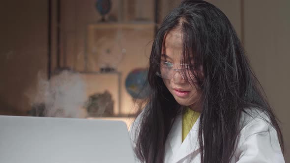 Young Asian Scientist Girl With Dirty Face Holding Test Tube And Work With Laptop Computer