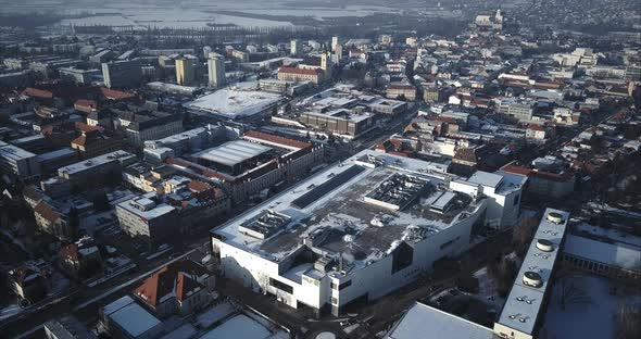 Flying above big shopping centre towards main intersection in Nitra City, Winter, Aerial shot, Slova