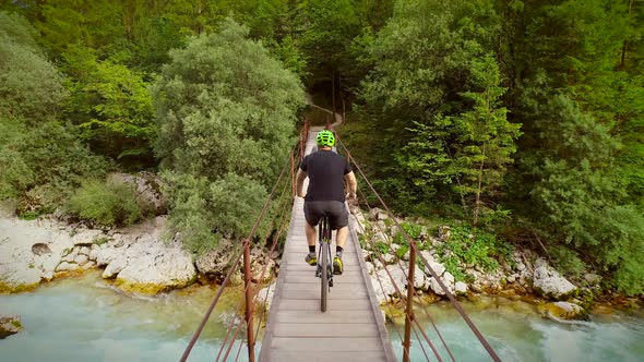 Aerial view of a man on a bicycle crossing wooden bridge at the Soca River.