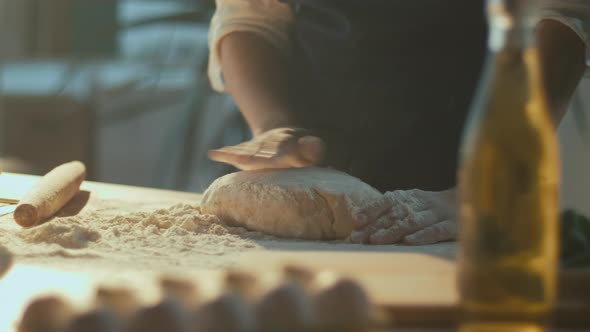 Smiling Woman Baker with Delight Sprinkles Flour on The Dough on the Table