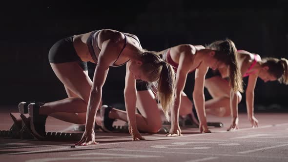 A Row of Runners Womens Crouch in the Starting Position Before Beginning to Race