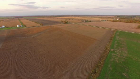 Patterns and colors of flat, wide open farms in the heartland at sunset. Fall colors on the trees an