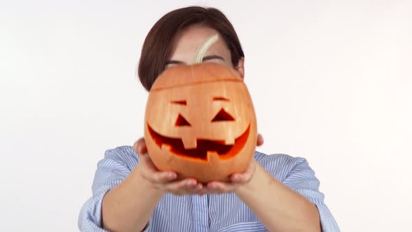 Woman Hiding Her Face Behind Carved Halloween Pumpkin