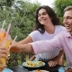 People Toasting Juice Glasses Sitting At Table On Terrace Eating Young Friends Talking Outdoors - VideoHive Item for Sale