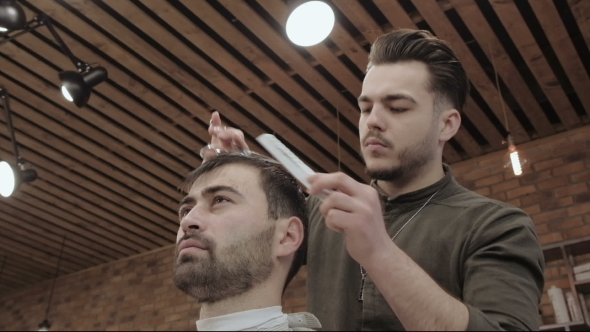 Master Cuts Hair and Beard of Men in the Barbershop, Hairdresser Makes Hairstyle for a Young Man