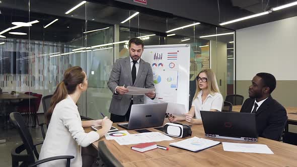 Businessman in Suit Standing Near Flip Chart Presentation and Talking 