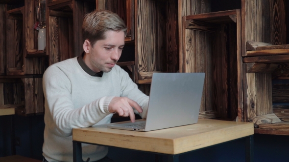 Man Freelancer Working on Laptop Computer in Cafe
