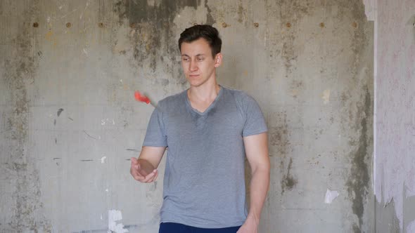 Man Standing in Room of Renovating Apartment and Juggles with a Spatula