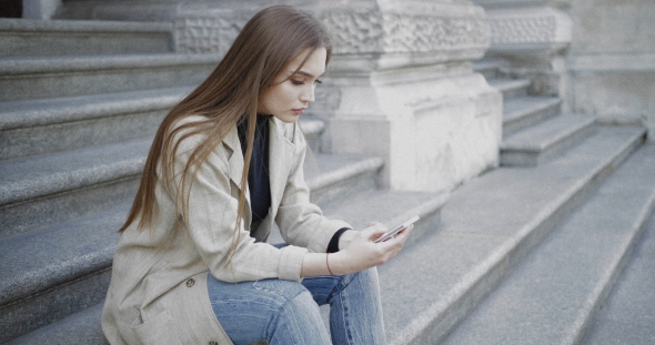 Woman Using Smartphone While Sitting on Stairs