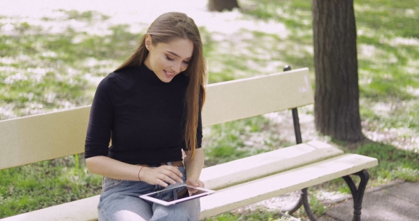 Cheerful Young Woman Using Tablet Outside