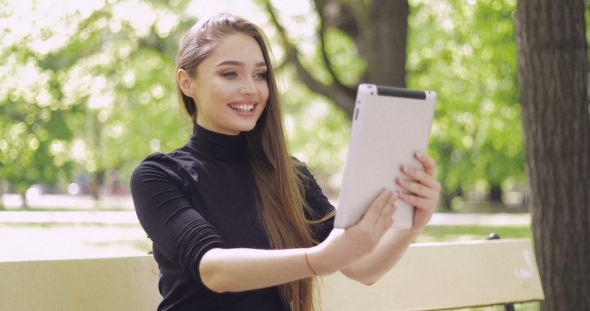 Smiling Woman Using Tablet in Park
