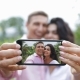 Couple Hold Cell Smart Phone Take Selfie Photo Embracing Kissing Outdoors Over Tropical Forest - VideoHive Item for Sale