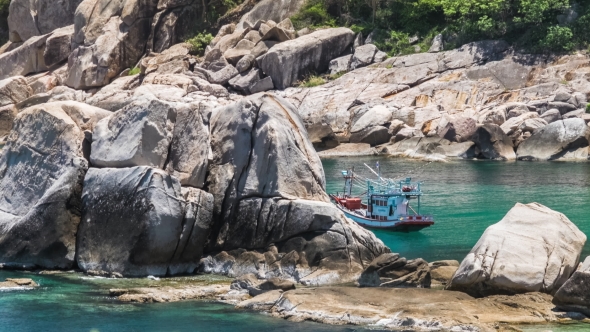 Fisher Boat Moving on Waves at Anchor Between Huge Stone Blocks in Tanote Bay, Koh Tao Island