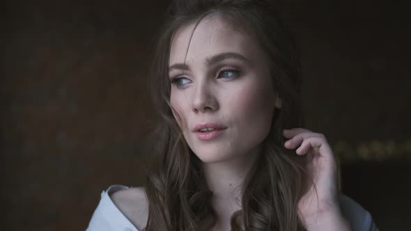 Portrait of an Attractive Girl in a White Blouse Close-up. Beautiful Blue-eyed Model Looking Into