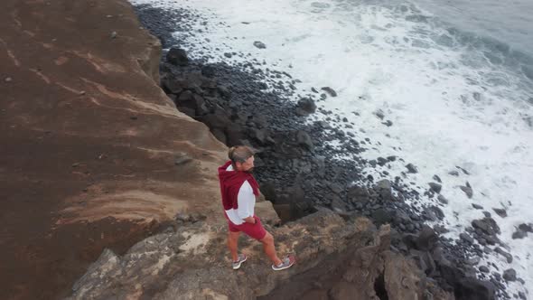 A Tourist Stands on the Edge of the Shore Surrounded with Ocean Waters