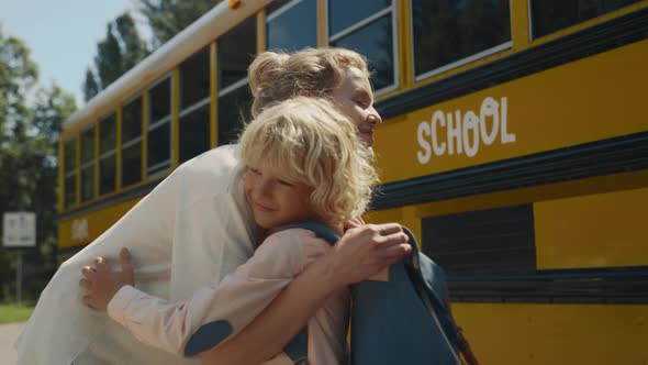 Smiling Mom Hugging Son Near School Bus