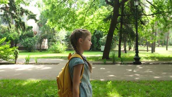 Kid Elementary School Student Walks Through the Park to School in the Morning