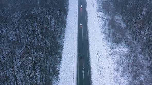 Aerial View of Traffic on the Road Passing Through the Winter Forest in Winter