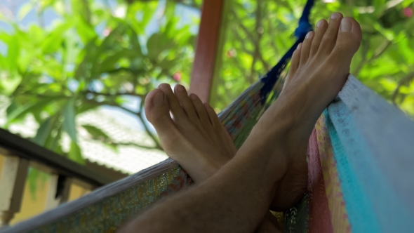 Swinging Bare Man Feets in a Hammock on Terrace. Vacation on Koh Tao Tanote Bay, Thailand