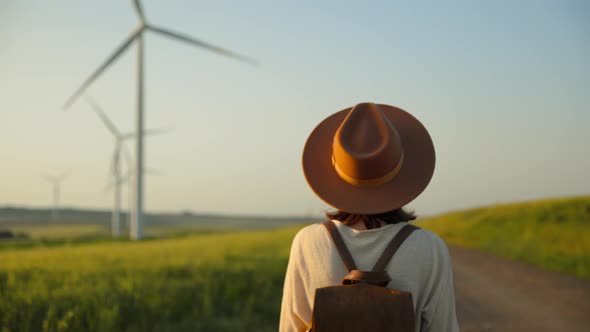 Beautiful tourist in a hat with eco windmills in a field