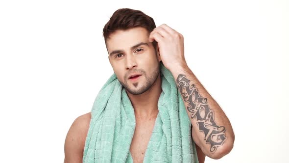 Confident Caucasian Topless Male with Light Bristle and Towel Around His Neck Touching His Hair and