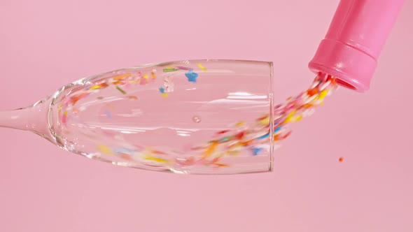 Colorful Candy Confectionery Run Poured Into a Wineglass Glass on Pink Background