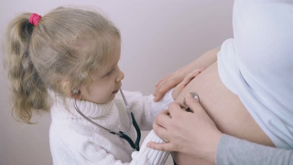 Girl with Stethoscope Listens To Baby in Pregnant Mom Tummy