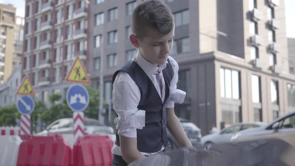 The Little Boy Rolls Up the Sleeves and Raises the Hood of the Car