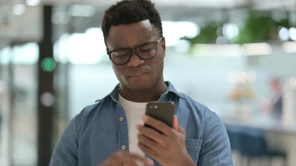 Portrait of African Man Having Loss While Using Smartphone