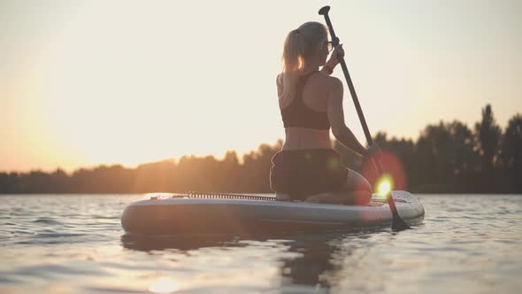 Girl Floating On Sup Board At Idyllic Evening. Swimming On Stand Up Paddle Board. Surfer Water Sport