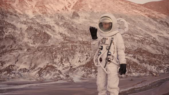 an Astronaut in a Stream Finds a Stone and Examines It