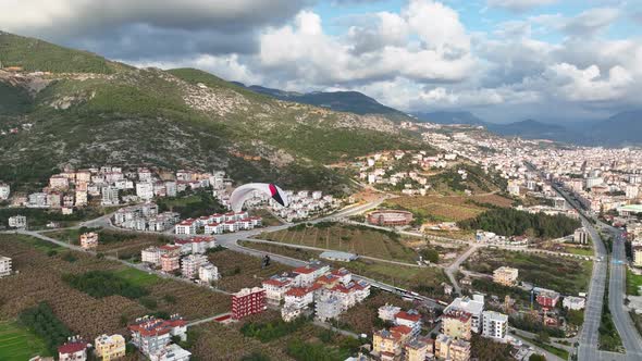 Aerial drone view of parachute jumper flying over beautiful Alanya