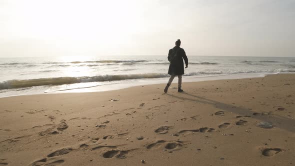 Thoughtful Lone Man Look at Sunrise Wave Ocean Horizon and Throw Stones to Water