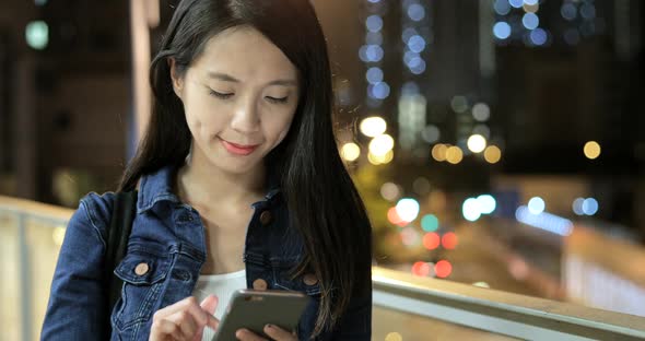 Woman using mobile phone in city at night 